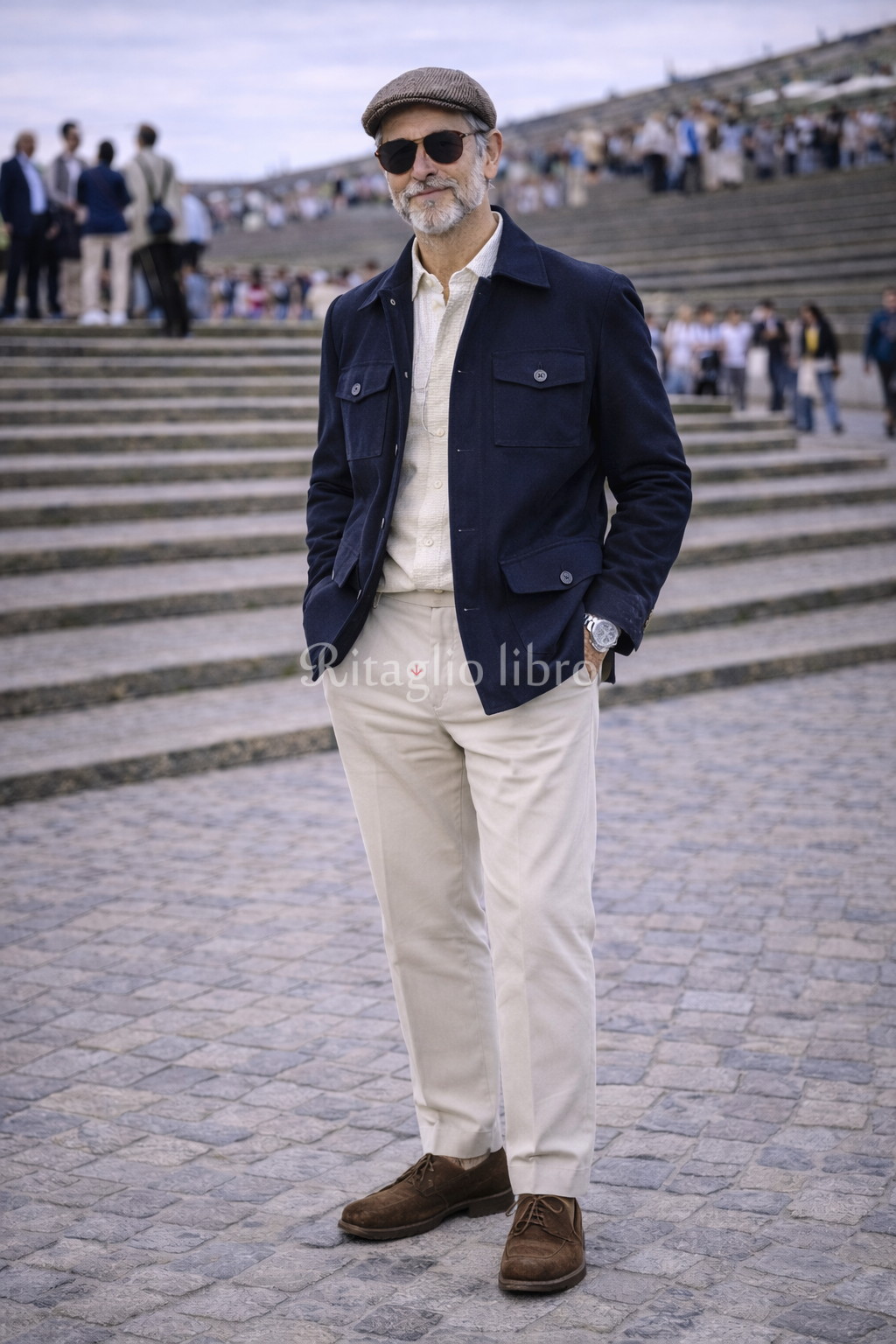 50代男性が、イタリアの街中で撮影した、ネイビーブルゾンとオフホワイトスラックスのコーディネートスナップ